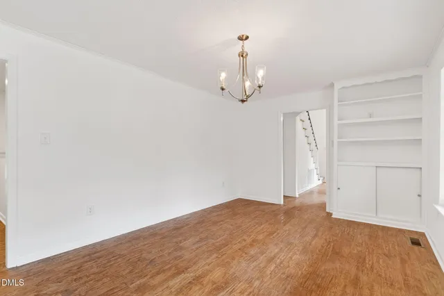 a view of an empty room with window and wooden floor