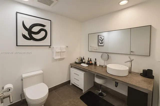 a bathroom with a granite countertop sink mirror vanity and toilet