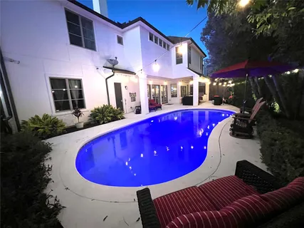 a view of a swimming pool with lawn chairs under an umbrella