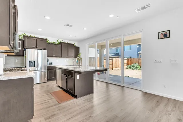 a kitchen with a sink a refrigerator and a stove top oven with wooden floor