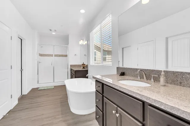 a bathroom with a sink double vanity granite tub and a window