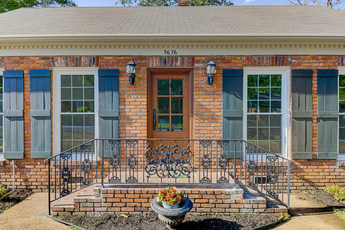 5676 Barfield Road Memphis, TN 38120 - Photo 19 of 19 Brick exterior with a wooden entry door, flanked by shuttered windows
