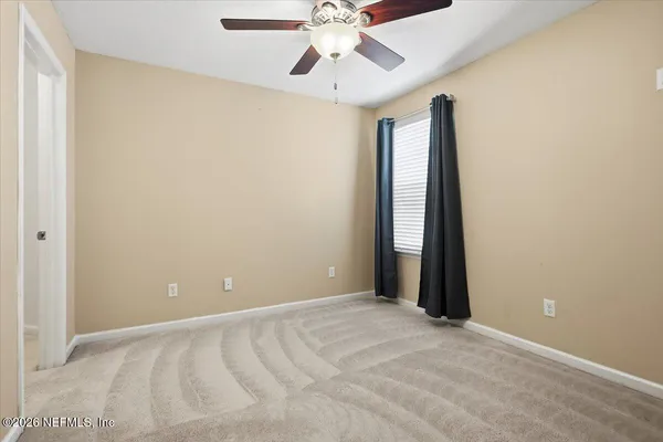 an empty room with chandelier fan and windows