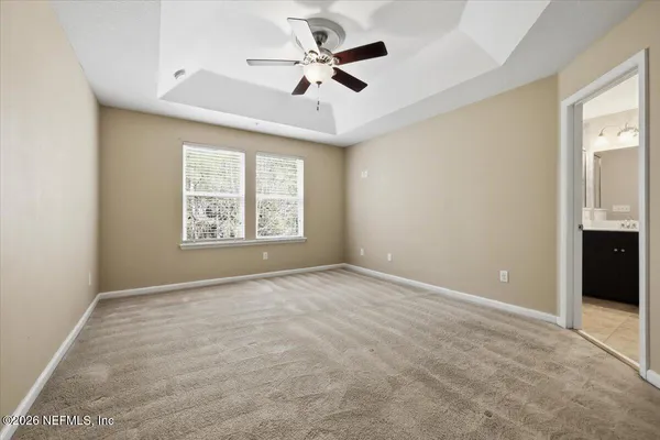 an empty room with windows and ceiling fan