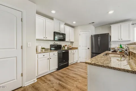 a kitchen with granite countertop a refrigerator and a sink