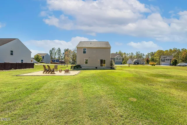 a view of residential houses with yard and trees in the background