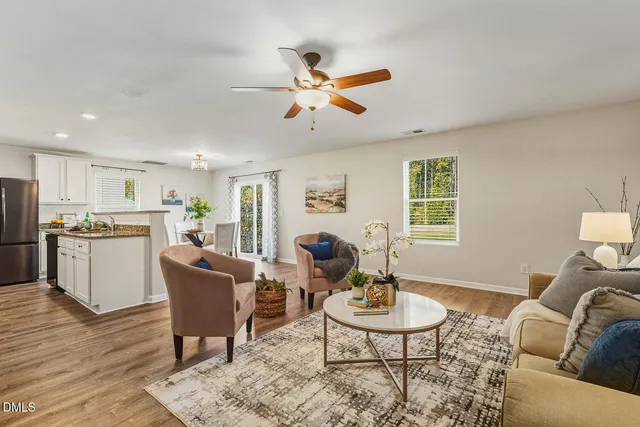 a living room with furniture kitchen view and a window