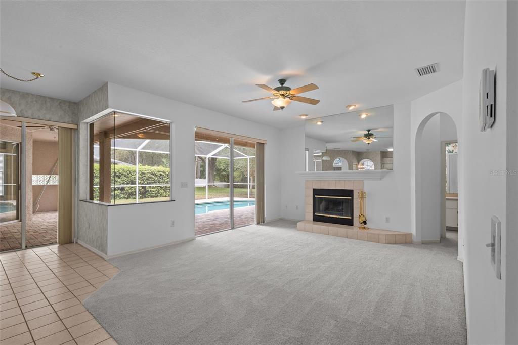 18543 Bittern Avenue Lutz, FL 33558 - Photo 32 of 45 a view of a livingroom with a fireplace a ceiling fan and windows