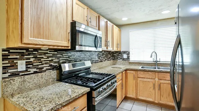 a kitchen with stainless steel appliances granite countertop a refrigerator and a sink