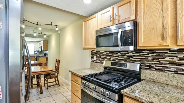 a kitchen with granite countertop a refrigerator a sink and white cabinets