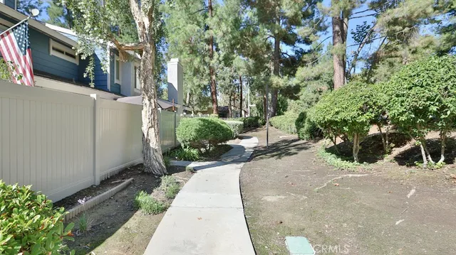a view of a backyard with potted plants and large trees