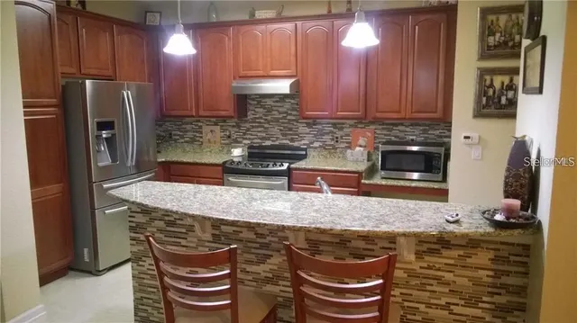 a kitchen with stainless steel appliances granite countertop a sink a stove and a refrigerator