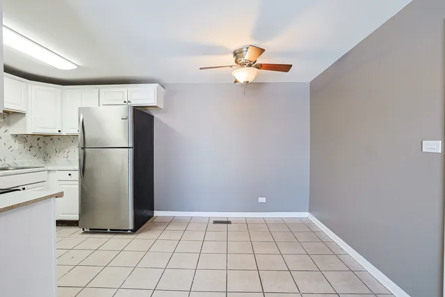 a kitchen with a refrigerator and white cabinets
