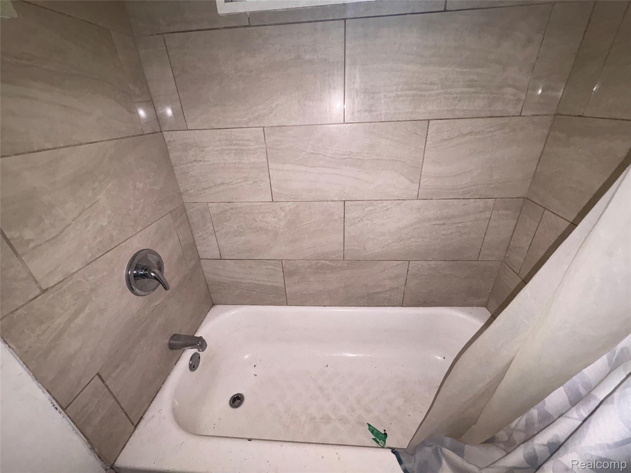 17655 Sunderland Road Detroit, MI 48219 - Photo 12 of 23 Tiled shower surround with a chrome faucet and tub filler