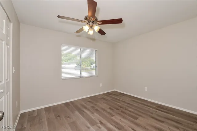 an empty room with wooden floor fan and windows