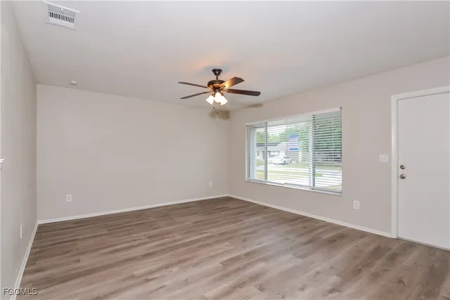 a view of an empty room with wooden floor and a window