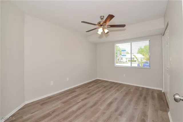 an empty room with windows and ceiling fan