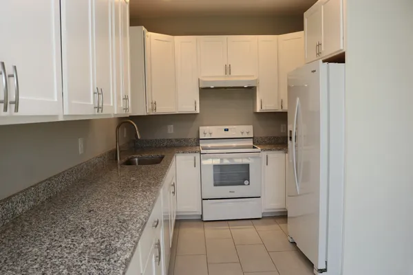 a kitchen with stainless steel appliances granite countertop a sink a stove and a refrigerator