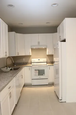 a kitchen with granite countertop white cabinets and white appliances