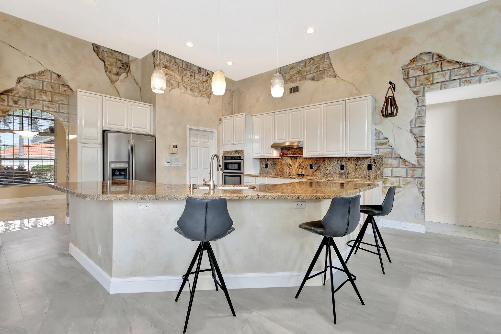 19236 Bay Leaf Court Boca Raton, FL 33498 - Photo 26 of 100 a kitchen with stainless steel appliances kitchen island a table chairs in it and wooden floors