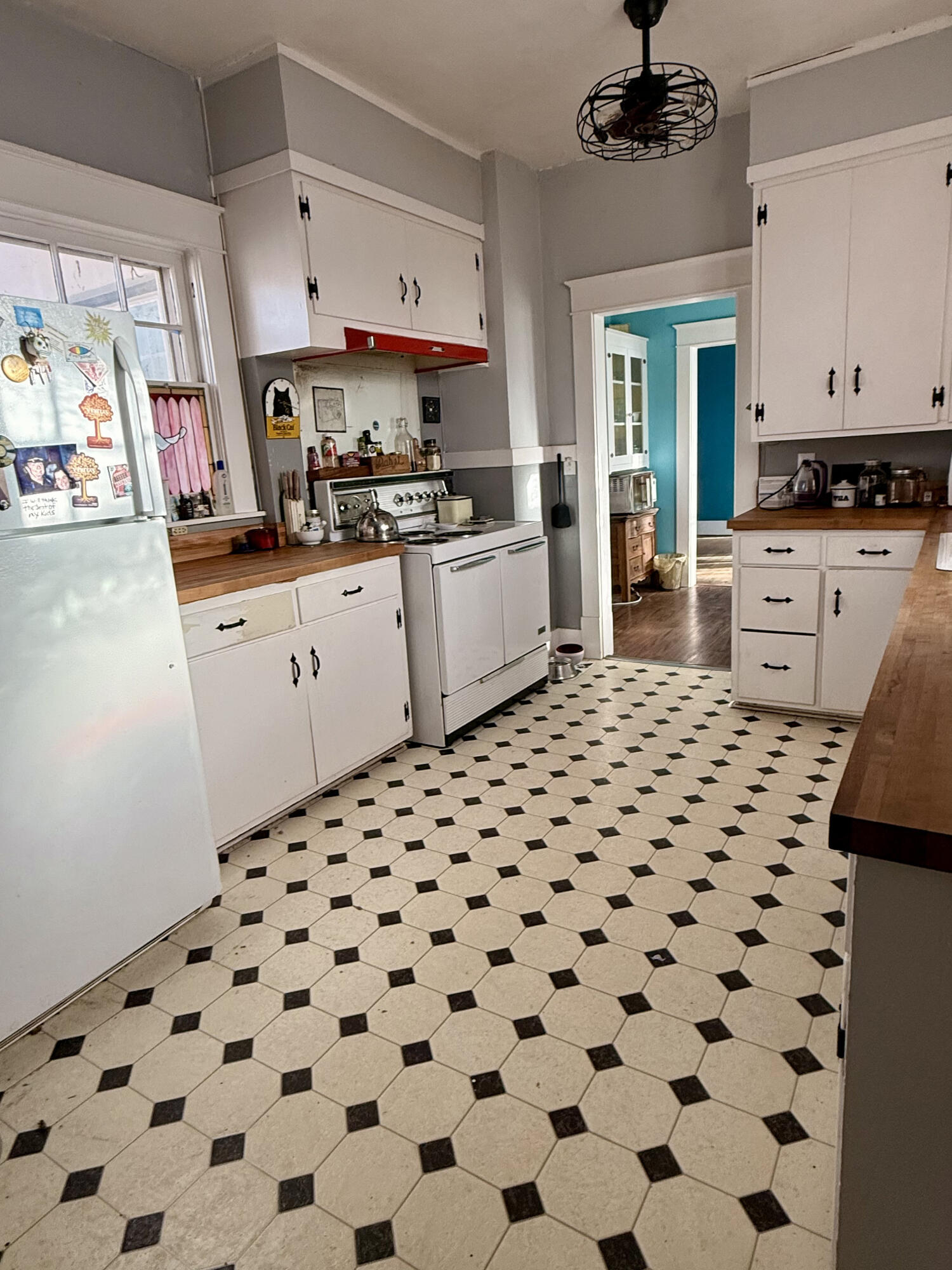 302 West 10th Street Post, TX 79356 - Photo 15 of 30 a kitchen with a checkered floor and white cabinets