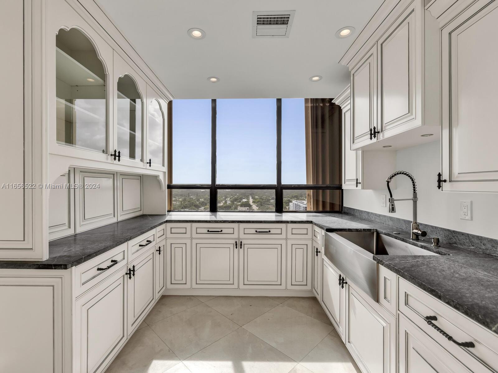 11113 Biscayne Boulevard, Unit PH5 Miami, FL 33181 - Photo 12 of 58 a large white kitchen with stainless steel appliances granite countertop a sink and dishwasher next to a large window