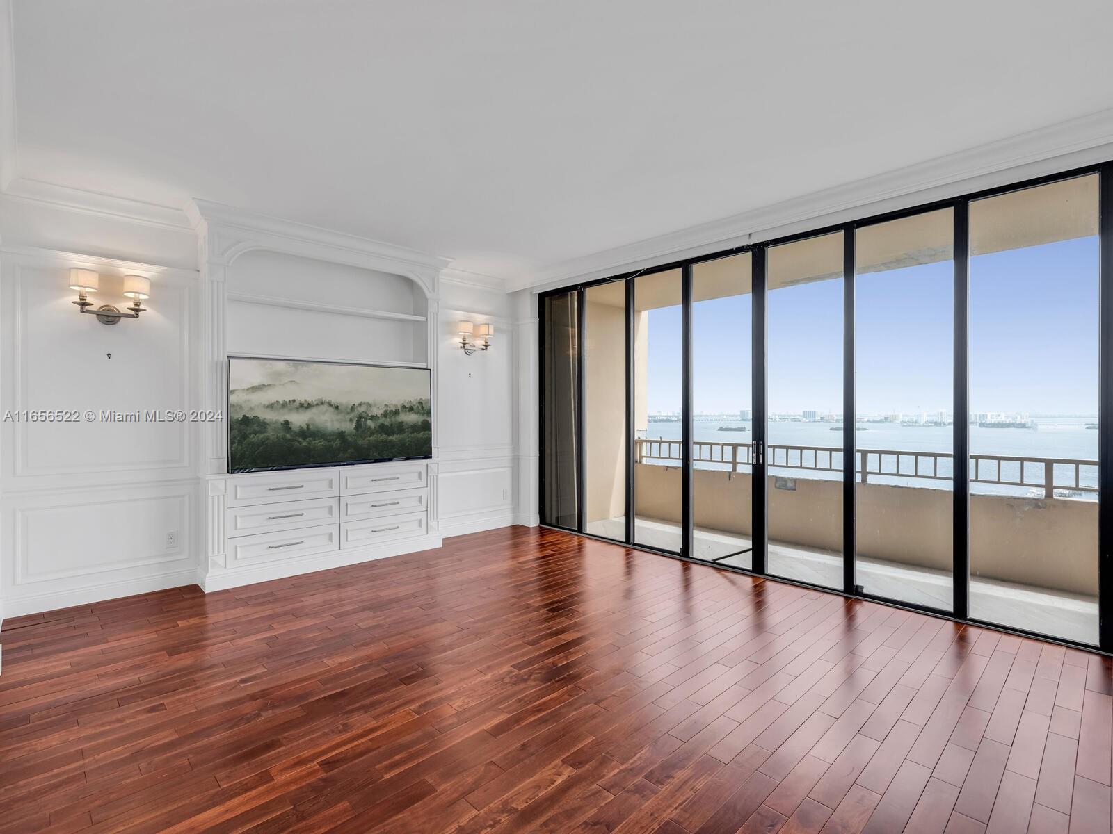 11113 Biscayne Boulevard, Unit PH5 Miami, FL 33181 - Photo 21 of 58 a view of an empty room with wooden floor and a floor to ceiling window