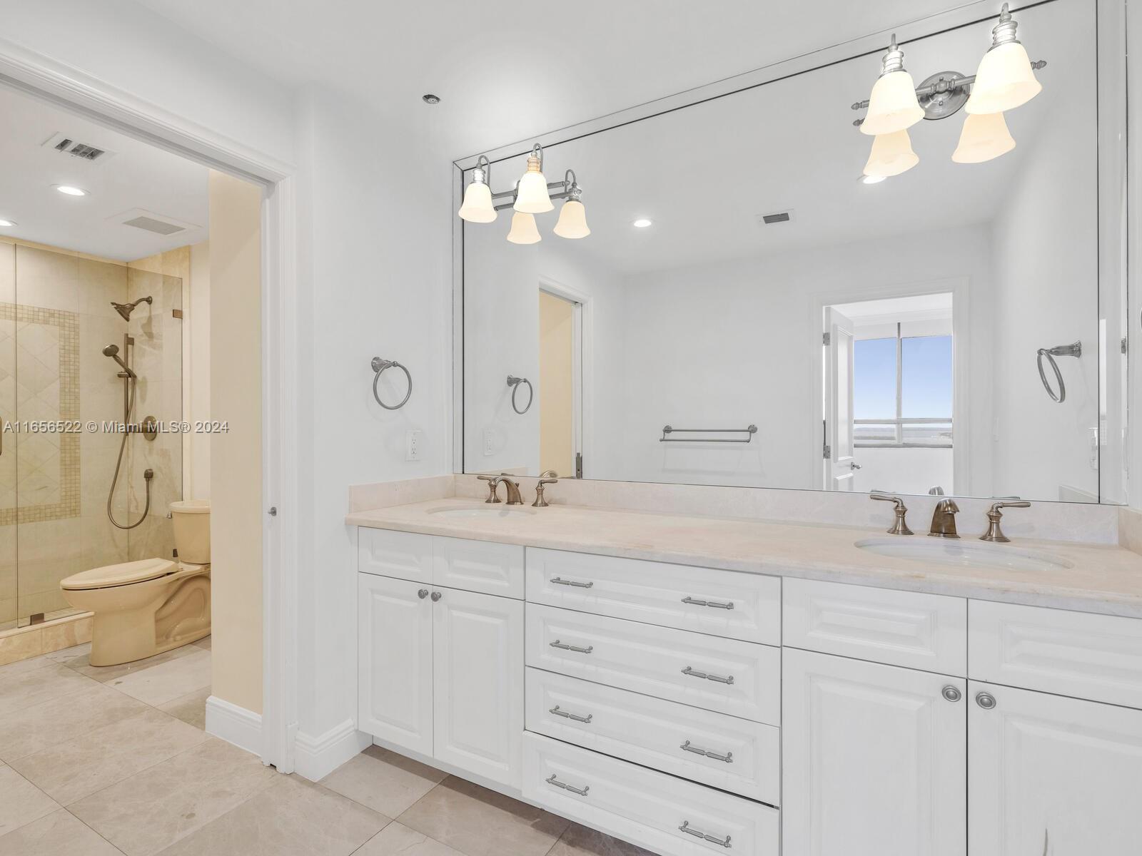 11113 Biscayne Boulevard, Unit PH5 Miami, FL 33181 - Photo 24 of 58 a bathroom with a granite countertop sink a toilet and a large mirror