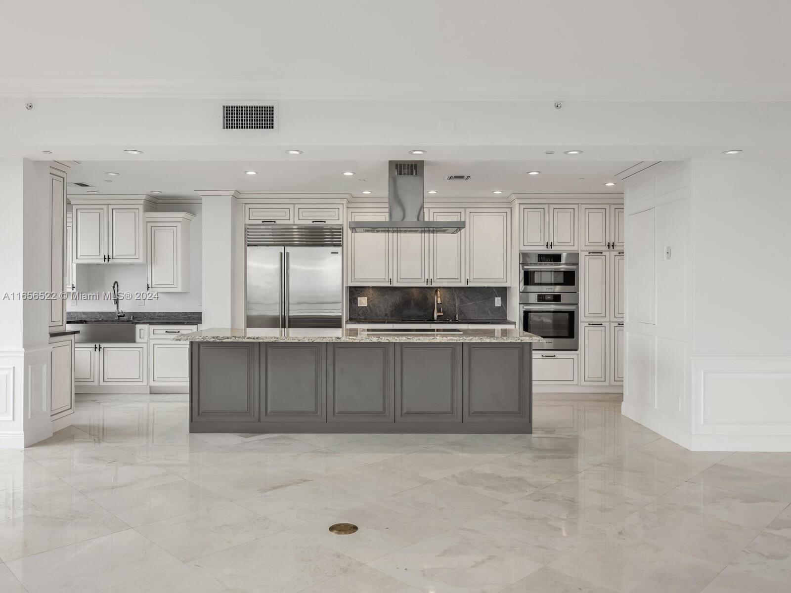 11113 Biscayne Boulevard, Unit PH5 Miami, FL 33181 - Photo 9 of 58 a large kitchen with stainless steel appliances kitchen island granite countertop a stove a sink a refrigerator and white cabinets