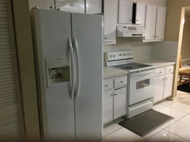 a kitchen with stainless steel appliances a refrigerator a stove and white cabinets