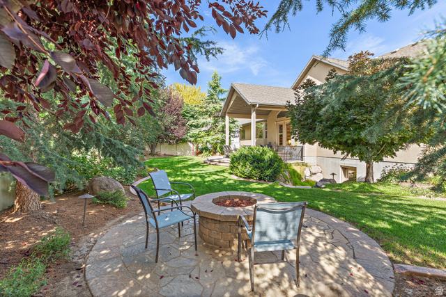 552 East Johns Way Sandy, UT 84070 - Photo 60 of 67 Backyard featuring a stone fire pit, stamped concrete patio, and mature landscaping