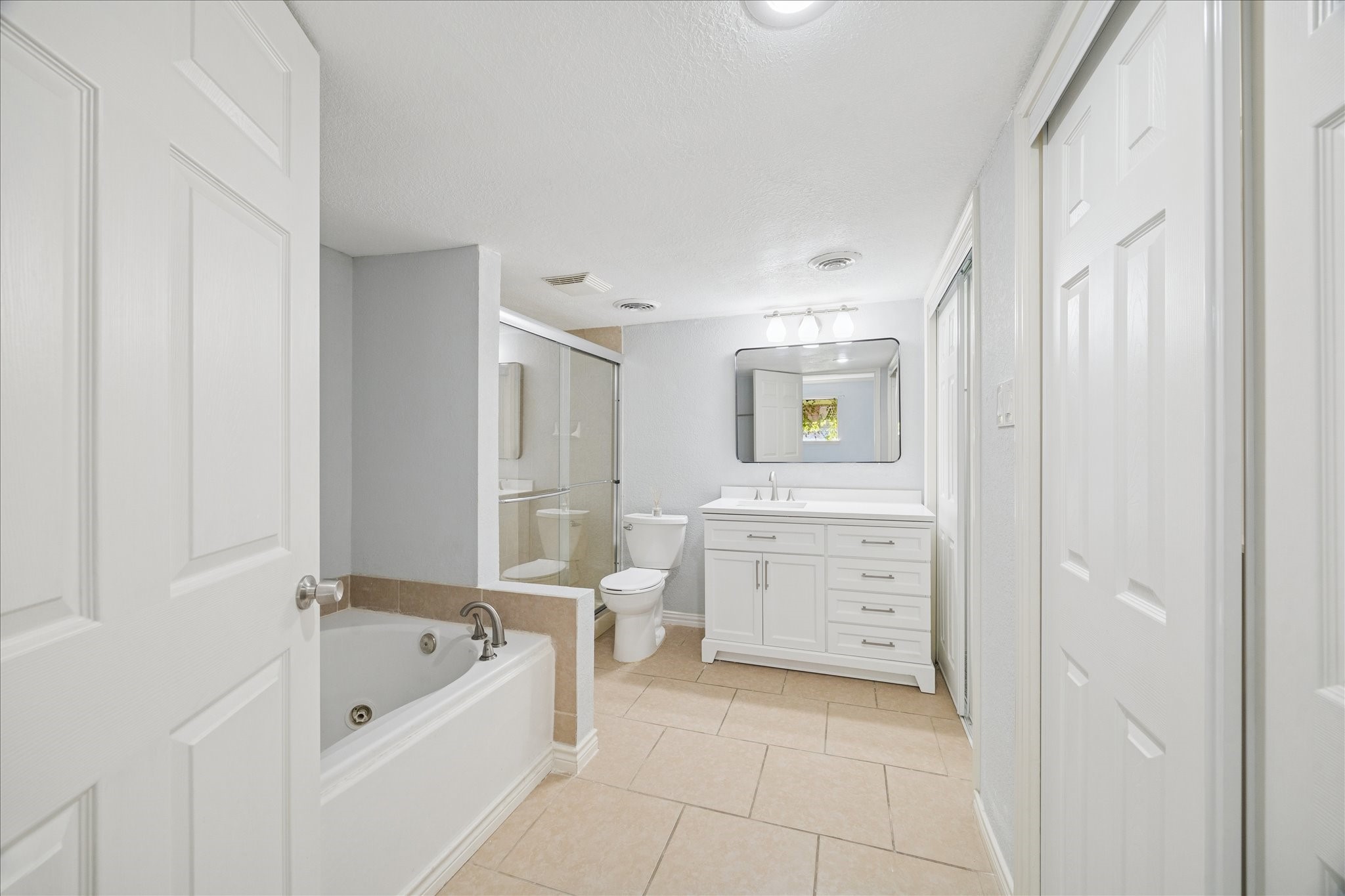 6304 Crab Orchard Road, Unit 6304 Houston, TX 77057 - Photo 15 of 23 Spa-like en suite bathroom featuring a separate glass-enclosed shower, whirlpool soaking tub, vanity, and additional closet space for ultimate luxury and convenience.