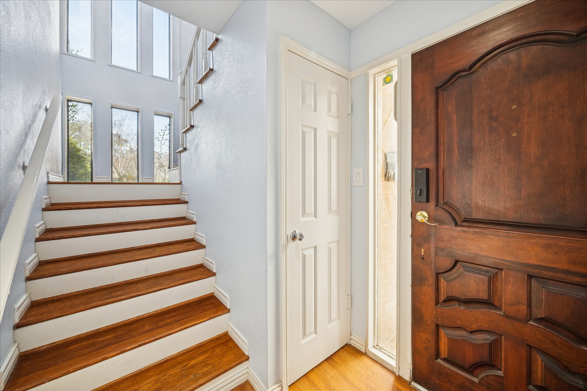 6304 Crab Orchard Road, Unit 6304 Houston, TX 77057 - Photo 4 of 23 Warm wooden steps paired with dramatic floor-to-ceiling picture windows, creating a light-filled and inviting entry. Notice the additional storage space located near the front door.