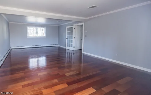 a view of empty room with window and wooden floor