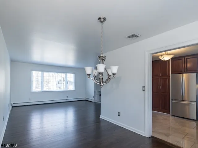 a view of a room with wooden floor chandelier and windows
