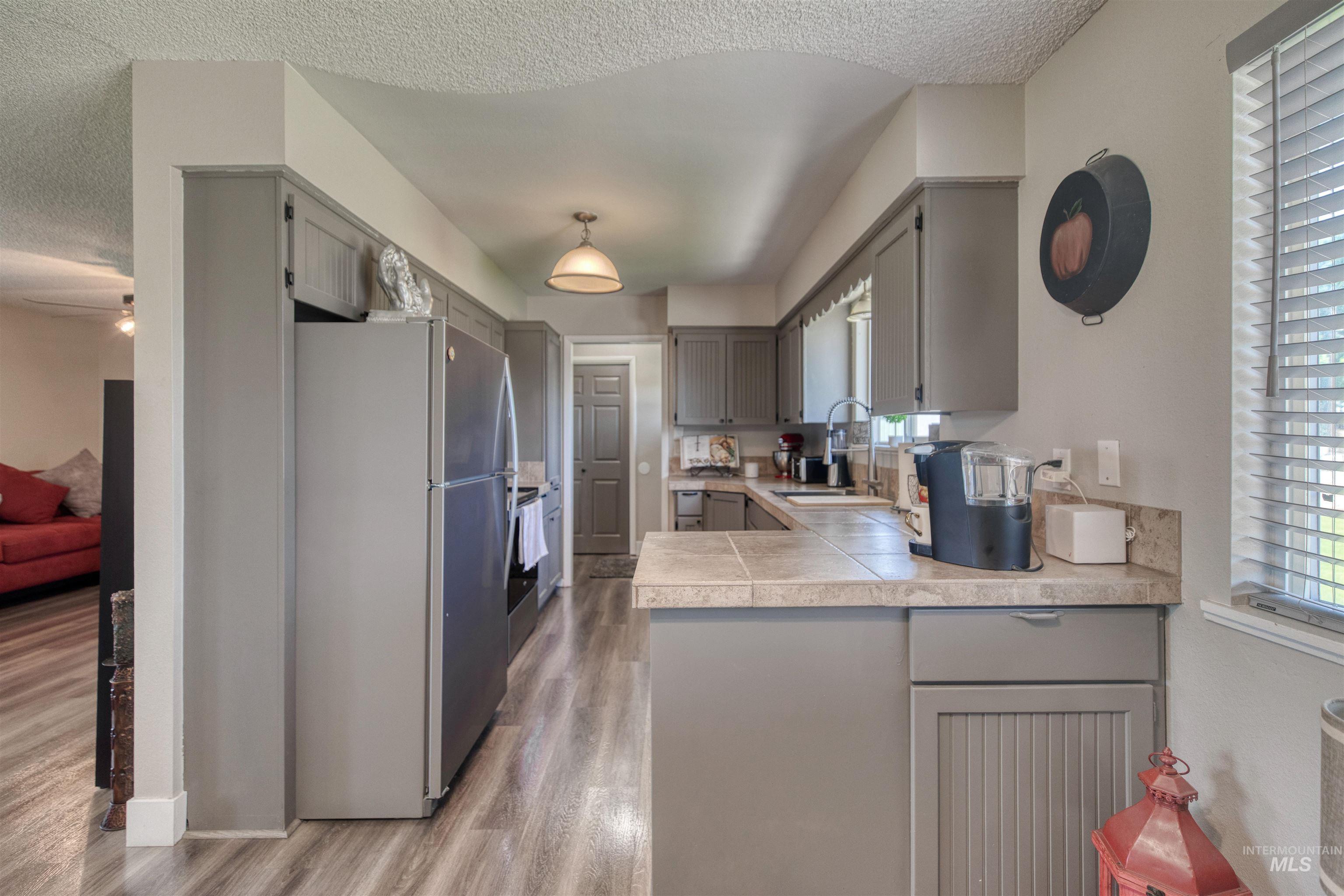 20803 Friends Road Greenleaf, ID 83626 - Photo 39 of 39 Galley kitchen featuring wood-finish flooring, gray cabinetry, and light-toned countertops