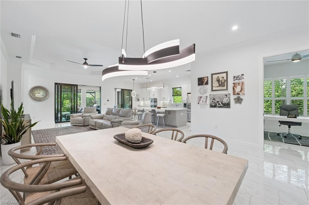 3171 Quilcene Lane Naples, FL 34114 - Photo 10 of 37 a view of a dining room and livingroom with furniture wooden floor a rug a potted plant and a chandelier