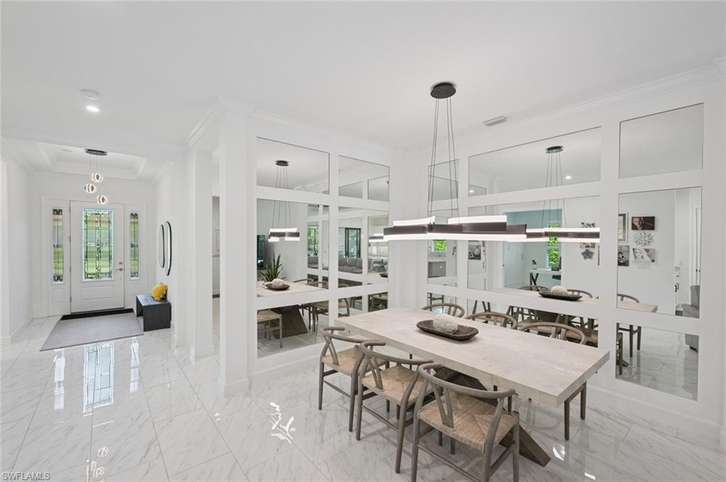 3171 Quilcene Lane Naples, FL 34114 - Photo 5 of 37 a kitchen with stainless steel appliances kitchen island granite countertop a dining table chairs and white cabinets