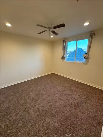 an empty room with a ceiling fan and window