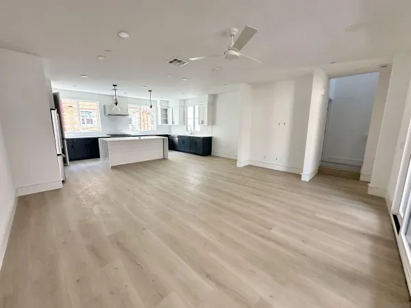 a view of an empty room with kitchen view and a window