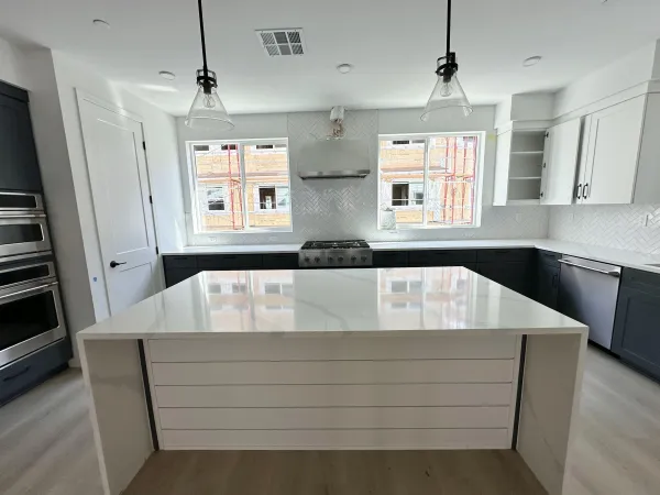a close view of kitchen island a sink dishwasher a stove and black appliances with wooden floor