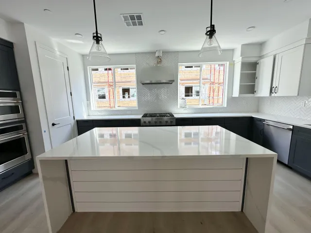 a close view of kitchen island a sink dishwasher a stove and black appliances with wooden floor