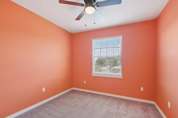an empty room with a window and a ceiling fan