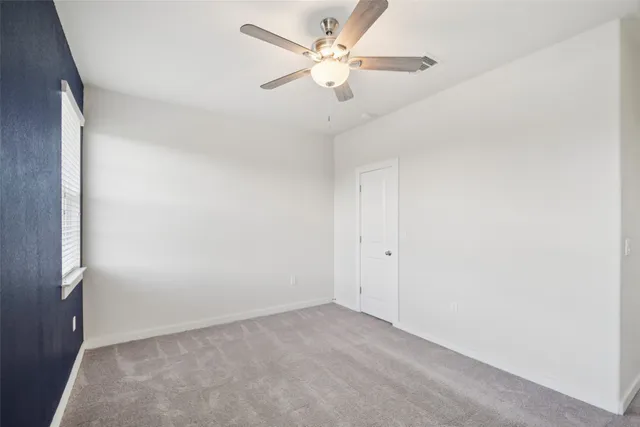 an empty room with a ceiling fan and a window