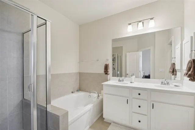 a bathroom with a double vanity sink mirror and bathtub