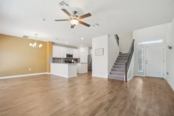 a view of an empty room with wooden floor and a ceiling fan