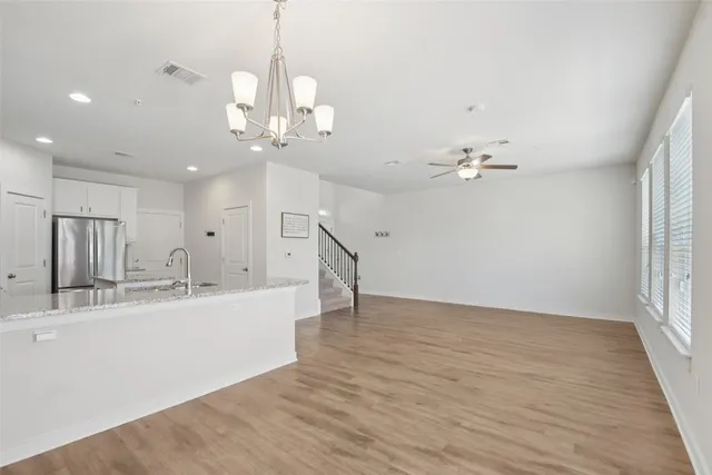 a kitchen with stainless steel appliances granite countertop a sink a stove and a refrigerator with wooden floor