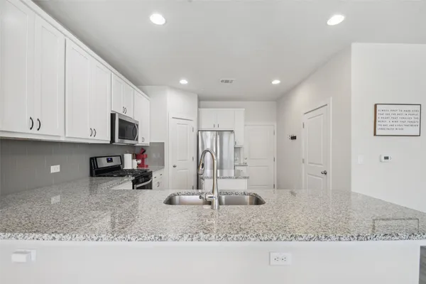 a kitchen with stainless steel appliances granite countertop a sink a stove and a refrigerator