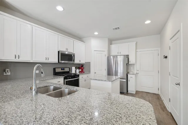 a kitchen with granite countertop white cabinets and white appliances