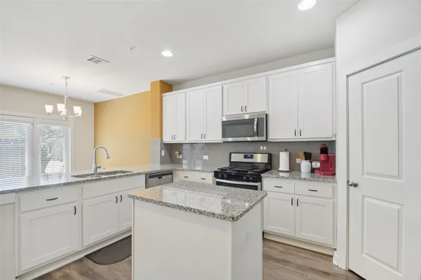 a kitchen with granite countertop white cabinets and white appliances
